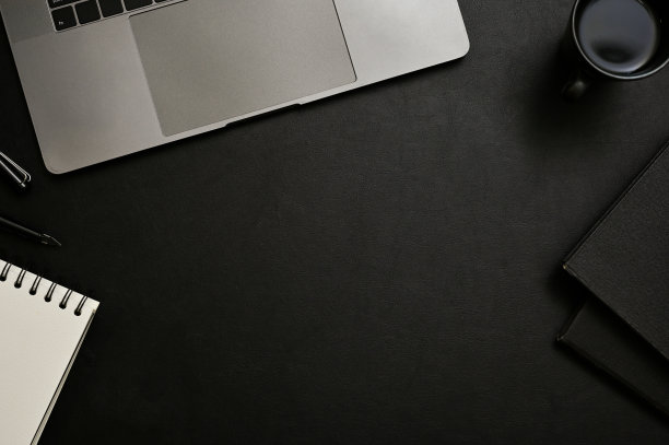 现代办公桌面顶视图与复制空间在中间，笔记本电脑，黑色背景上的装饰。图片下载