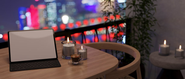 带无线键盘的平板电脑，晚上公寓阳台的桌子上放着蜡烛图片下载