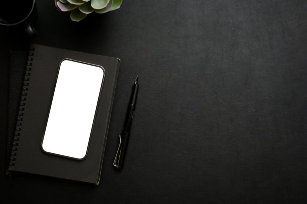 现代黑色桌面工作空间，智能手机模型，记事本，钢笔和复制空间。俯视图图片下载