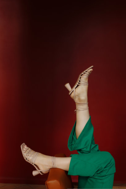 穿着凉鞋的腿，红色的背景。图片下载