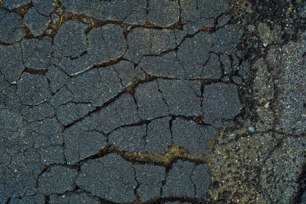 特写破碎的柏油路背景。图片下载