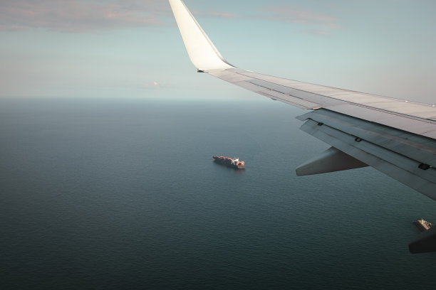 从飞机窗口看到的货运货船上蓝色的大海，而飞行运输的场景图片下载