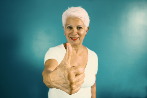穿着白衬衫的优雅老妇人竖起大拇指图片下载