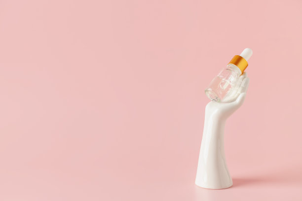 瓶与血清的手握在粉红色的背景。本空间图片下载