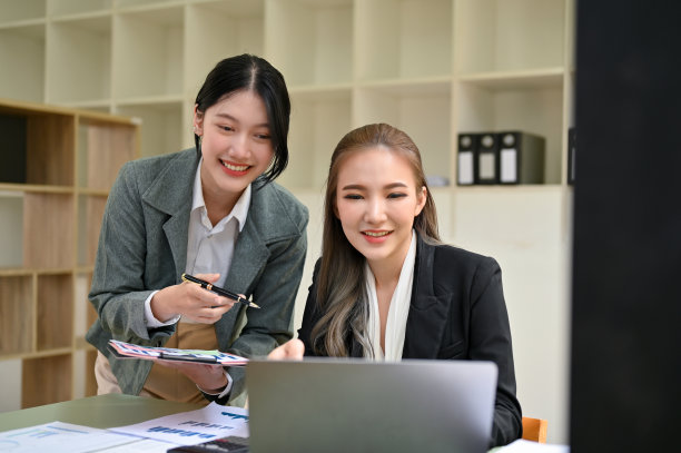 两位亚洲女商人在一起做她们的金融项目，看着笔记本电脑屏幕。图片下载
