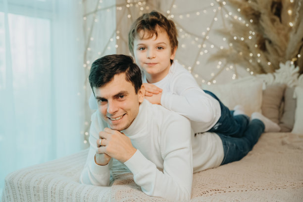 父亲和儿子穿着同样的白色毛衣躺在床上图片下载