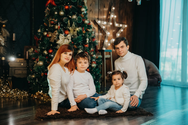 家里的妈妈，爸爸，哥哥和妹妹都穿着同样的白色毛衣坐在圣诞树旁边图片下载