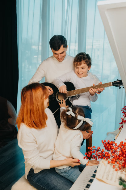 妈妈、爸爸、儿子和女儿正在他们的客厅里唱着、弹着圣诞歌曲。父亲和儿子弹吉他，母亲和女儿弹钢琴。图片下载