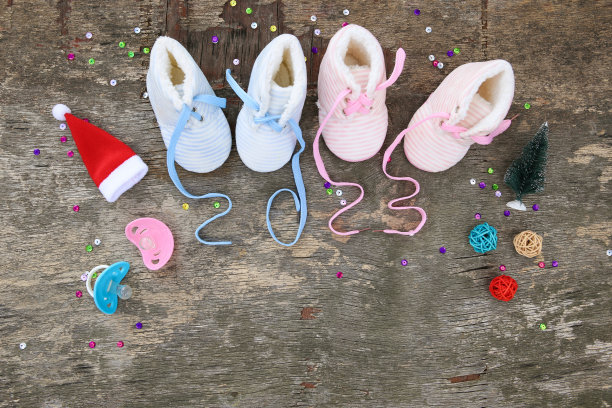 2023年新年写鞋带的儿童鞋和奶嘴在旧的木制背景。前视图。平的。文本空间。图片下载