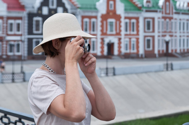 戴草帽的女游客拿着老式相机在街上拍照图片下载