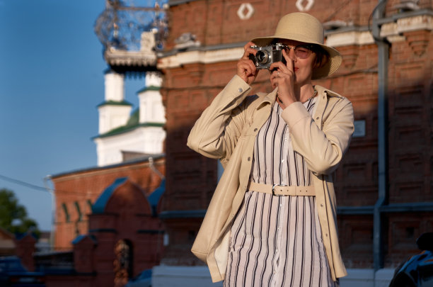 戴草帽的女游客拿着老式相机在街上拍照图片下载