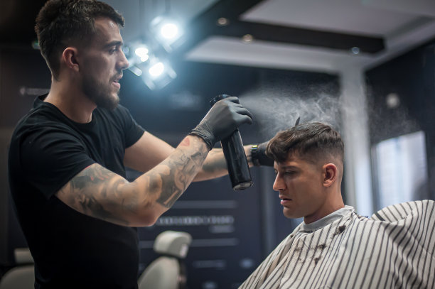 发型师用发胶喷发型。水滴在空气中可见图片下载