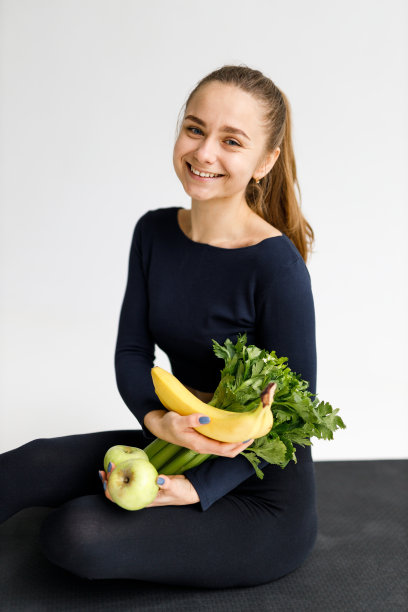 年轻的运动妇女与蔬菜在她的手在白色背景。图片下载
