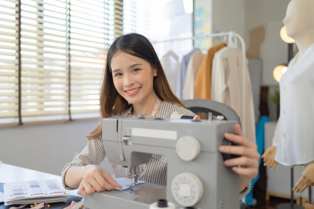 肖像自由设计师，裁缝，造型师艺术家亚洲妇女，泰国人工作在缝纫机，时装设计衣服和服装衬衫在家里。人们的生活方式。创新业务。图片下载