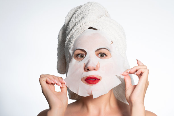 一个女人的肖像用棉花面膜滋润她的脸。图片下载