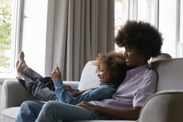 美丽的非洲青少年夫妇放松在沙发上与现代的小玩意图片下载