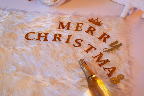 圣诞快乐写装饰文字与香槟瓶上的白色地毯。图片下载