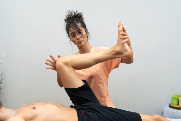 女物理治疗师对病人腿部进行物理治疗图片下载