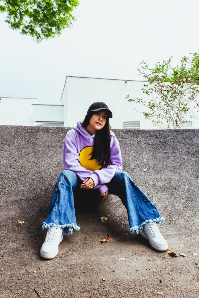 美丽的少女在运动衫和帽子坐在城市的城市风格图片下载