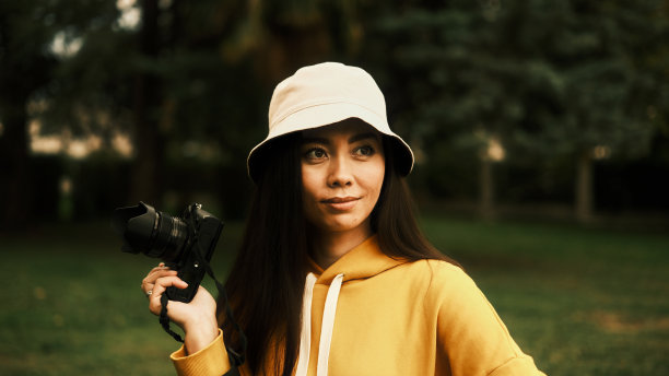 女孩一只手拿着相机，面带微笑图片下载
