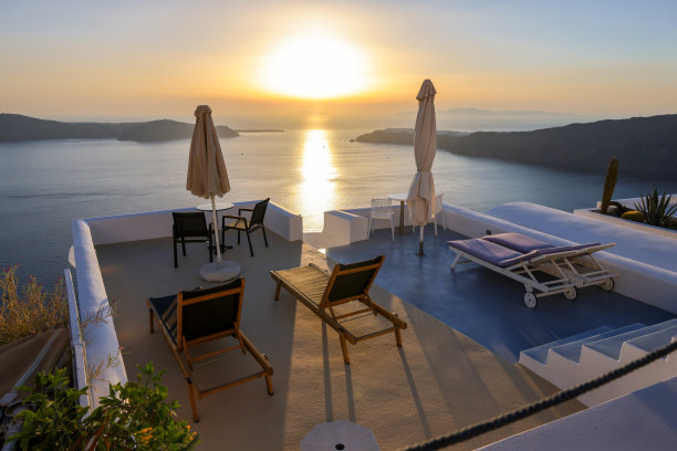 晒太阳的人在Imerovigli村的露台上，在圣托里尼岛的火山口上欣赏惊人的日落景色图片下载