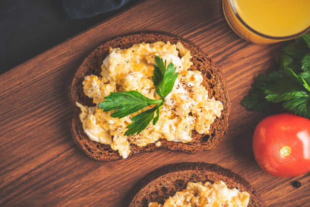 面包配欧芹炒鸡蛋，深色木板自制健康早餐，俯视图图片下载