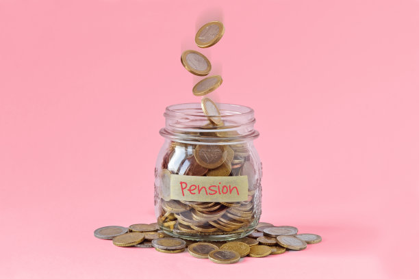 贴有印有“养老金”字样的标签和粉色背景上掉落的硬币的钱罐——女性和养老金的概念图片下载
