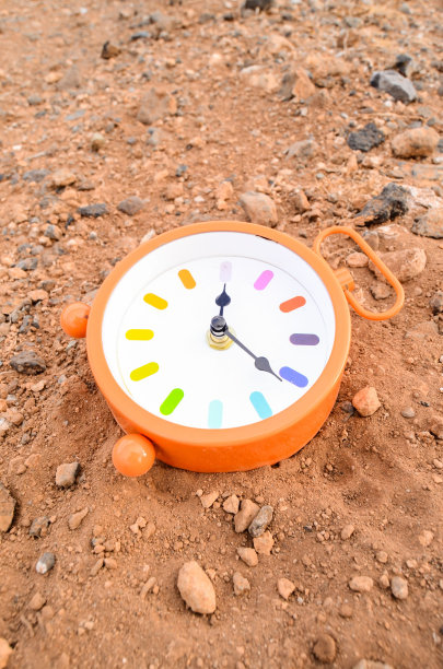 在岩石沙漠的沙子里放着经典的模拟时钟图片下载