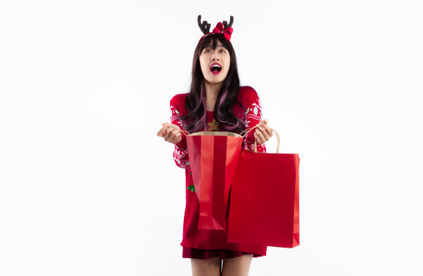 穿着红色运动衫、提着纸购物袋的亚洲妇女在白色背景下惊讶地摆姿势。图片下载