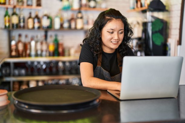 年轻的中国女服务员自信地微笑着在餐厅使用笔记本电脑图片下载