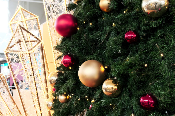 商场里圣诞树上漂亮的圣诞装饰品。金色和红色的圆形饰品图片下载
