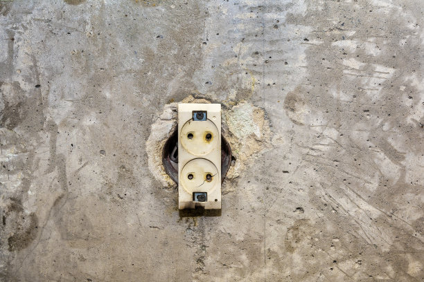 一堵又旧又脏的混凝土墙上一个烧焦的插座。火灾隐患图片下载