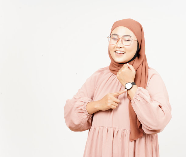 白色背景下戴着头巾的美丽亚洲女子的微笑和指着的手表图片下载