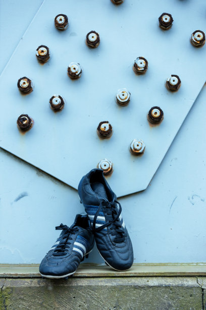 足球鞋站在金属建筑旁边。图片下载