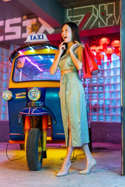 工作室肖像照片的一个美丽的年轻的亚洲女性模特与红色的纸购物袋摆出快乐的在曼谷的一辆嘟嘟出租车前面图片下载