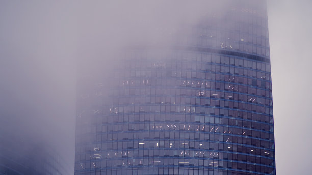 摩天大楼的窗户在雾中，背景复制空间。烟雾中的高层建筑的金属结构和窗户，特写图片下载