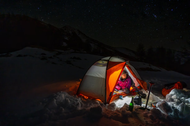 在星空下的雪地上露营的女人图片下载