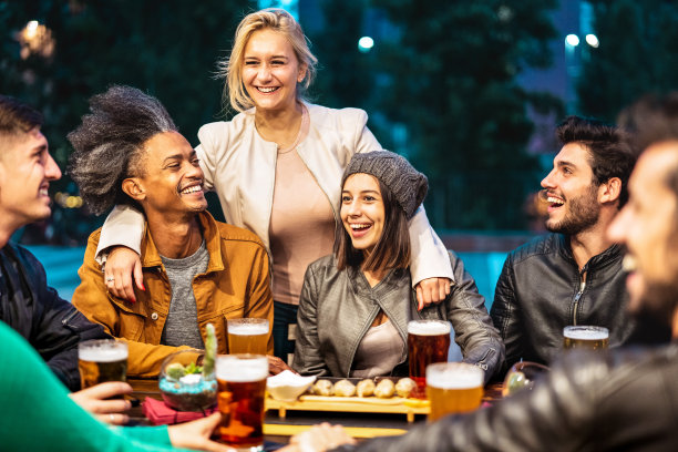 年轻人在啤酒厂酒吧露台喝啤酒-友谊的生活方式概念与千禧一代的朋友一起享受欢乐时光在露天酒吧-温暖的色调上生动的黄昏滤镜图片下载