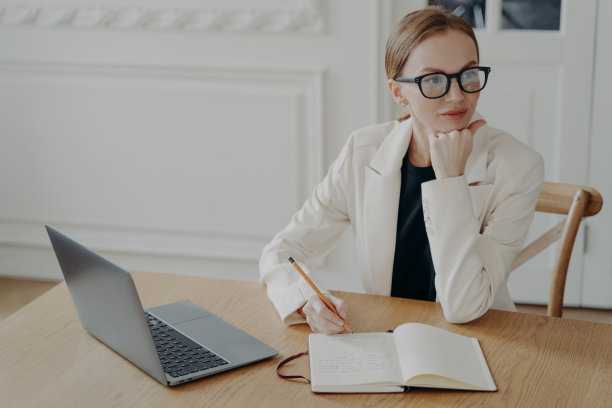 女商人在笔记本上写着，计划着工作日的日程安排，坐在办公桌旁用笔记本电脑图片下载