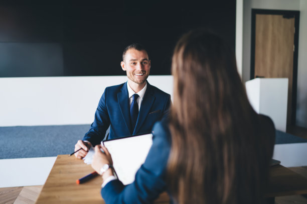 面带微笑的男经理与坐在桌旁的面无表情的同事讨论业务想法图片下载