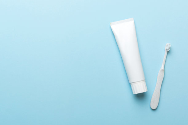 牙膏和牙刷顶部视图与彩色背景复制空间。平的。口腔卫生。口腔护理产品在光背景。身体护理概念图片下载