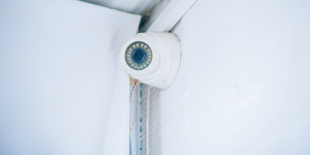 室内监控摄像头在天花板下的白墙上图片下载