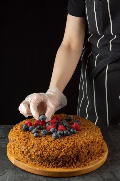 一位女厨师正在用新鲜浆果装饰一个自制的胡萝卜蛋糕，背景是深色的图片下载