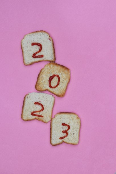 用番茄酱或番茄酱垂直写在吐司面包上，2023年新年快乐，祝福概念照片图片下载
