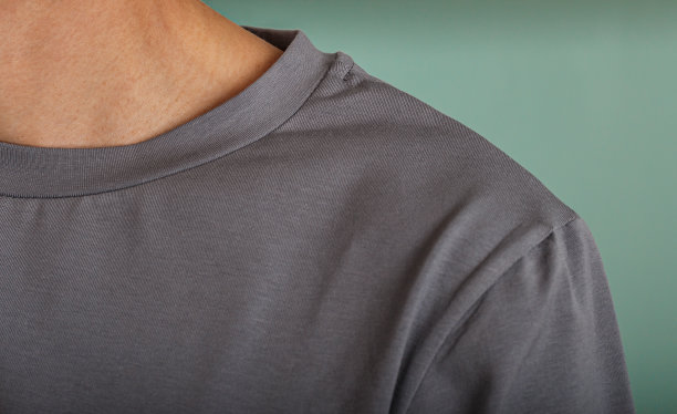 一个穿着灰色polo衫的男人出现在模糊的背景中。一个穿着灰色t恤的男人，一个宽松的特写镜头。图片下载
