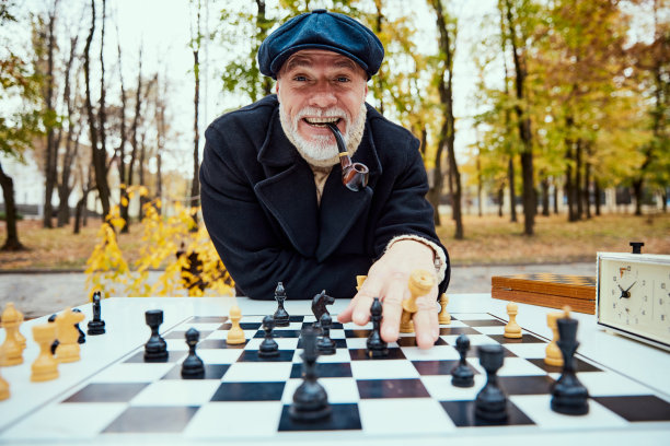 秋天的一天，一位老人在公园里下棋。赢得看。休闲活动观念，老一代图片下载