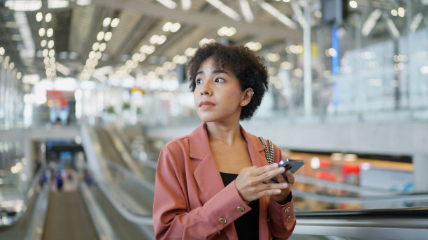 亚洲妇女在机场看短信微笑图片下载