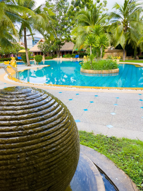 热带度假酒店大游泳池旁的圆石喷泉图片下载