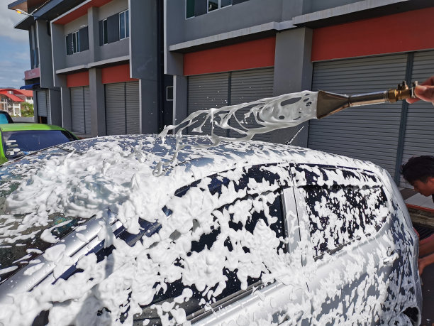 用白色肥皂和泡沫涂在车身上洗车的画面。图片下载