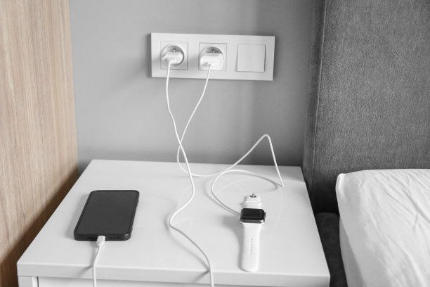 卧室里有充电的设备，床头柜上有充电的智能手表和手机图片下载
